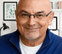 An interview portrait of Eric Cuthbert wearing glasses and a blue jacket, with a bald head and a calm, confident expression.